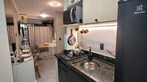 Een kleine keuken met een ingebouwde magnetron, een spoelbak en een fornuis.