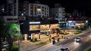 Een McDonald's restaurant met een modern design, naast een Duron Super Mercados winkel.