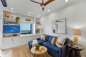 Ein Wohnzimmer mit blauem Sofa, Fernseher und Deckenventilator.