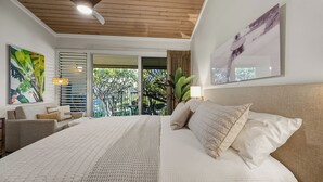 A bedroom with a large bed, a ceiling fan, and a balcony with a view of greenery. - Walk to Beach and Dining + AC - Napili Shores D224 - Updated Studio (Lahaina)