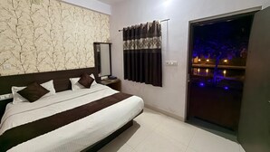 Une chambre d’hôtel avec un grand lit, une table de chevet, un miroir et une vue sur la ville la nuit.