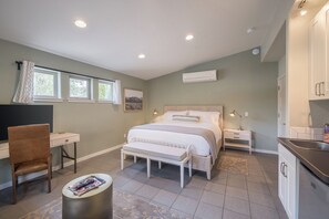 A bedroom with a bed, bedside tables, a desk, a chair, and a small round table with magazines. - The Entrada #1 at Westside Flats - Downtown Moab (Moab)