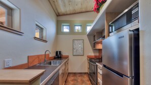 Una cocina compacta con un refrigerador de acero inoxidable, una cafetera y un lavamanos.