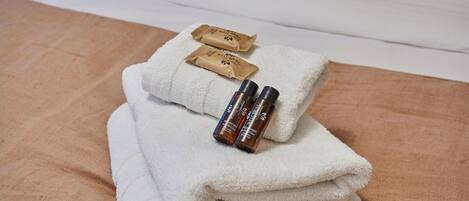 A neatly folded white towel with two small brown packages and two brown bottles on top.