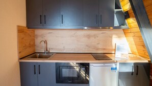 A compact kitchen with grey cabinets, a stainless steel sink, a microwave, and a small refrigerator. - Velvet Retreat The Golden Cabins With Garden (Gjinar)