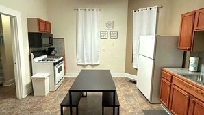 A kitchen with a black table, white appliances, and wooden cabinets.