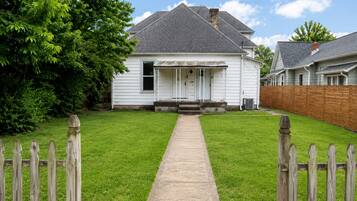 A single-story house with a front porch, a wooden fence, and a well-maintained lawn.