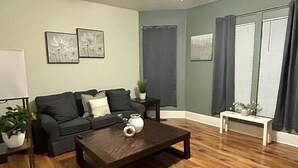 A living room with a dark wooden coffee table, a sofa, and a small white table with a plant.