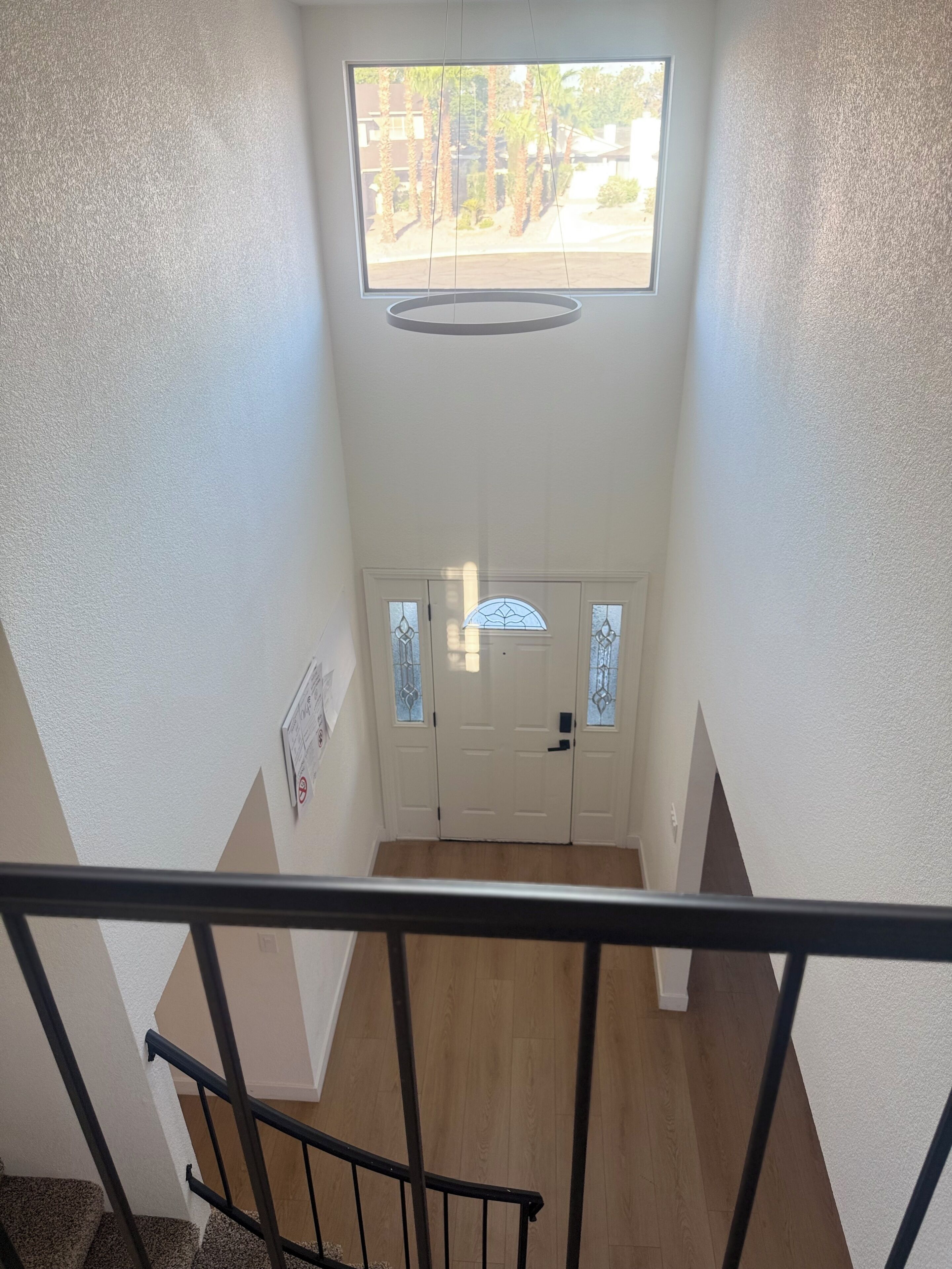 A staircase leading to a door with a window above, a handrail, and a sign on the wall.