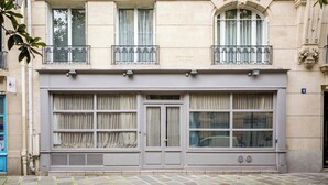 A building facade with a large window, a balcony with metal railings, and a door with a window. - Place des Vosges, Apartment With Air Conditioning (Paris)