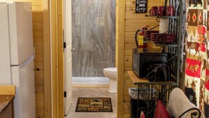 Interior em madeira com cozinha, banheiro com chuveiro e sala de jantar.