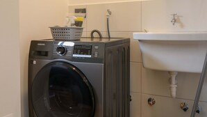 A compact laundry room with a front-loading washing machine, a sink, and a water heater. - w Engaging Loft in the Heart of San Isidro (Lima)