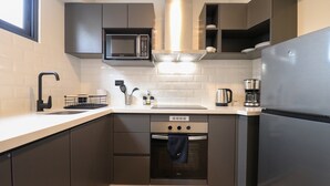 A modern kitchen with dark cabinetry, a stainless steel refrigerator, a built-in microwave, and a coffee maker. - w Engaging Loft in the Heart of San Isidro (Lima)