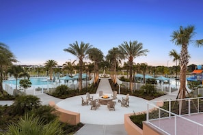 A pool area with lounge chairs and a fire pit, surrounded by palm trees and umbrellas. - Upstay Solara Resort Villa Pool Cinema Games (Kissimmee)