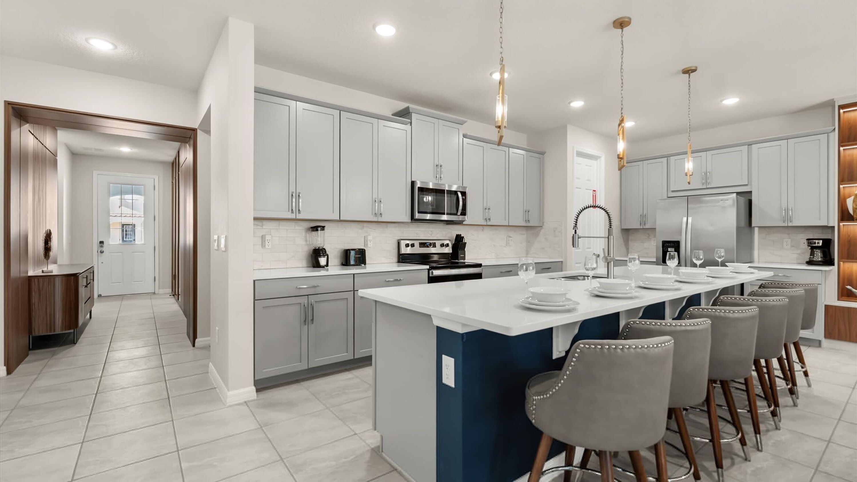 A modern kitchen with white cabinets, stainless steel appliances, and a central island with bar stools.