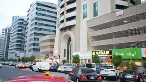 A busy urban street with modern buildings, a prominent 'Nawabi' sign, and a 'Krove' sign. - Contemporary Partition Room in Tecom  (Dubai)