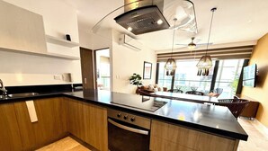 Een moderne keuken met een groot eiland, een inbouwoven en roestvrijstalen apparatuur.
