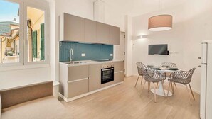 Una cucina moderna con forno integrato, un'area pranzo con un tavolo rotondo e sedie, e un televisore montato a parete.