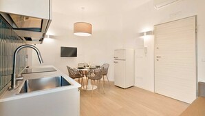 Una cucina moderna con lavello integrato, una zona pranzo con tavolo e sedie e un frigorifero bianco.