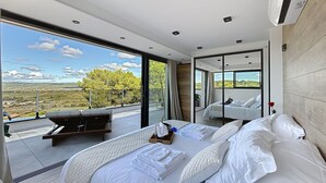 A modern bedroom with a large bed, a seating area, and a balcony with a scenic view. - L'Eden Bleu in Langlade, upscale romantic suite with private SPA. (Langlade)