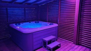 Ett bubbelbad med en trädeck och trappsteg som leder upp till det, omgivet av träväggar.