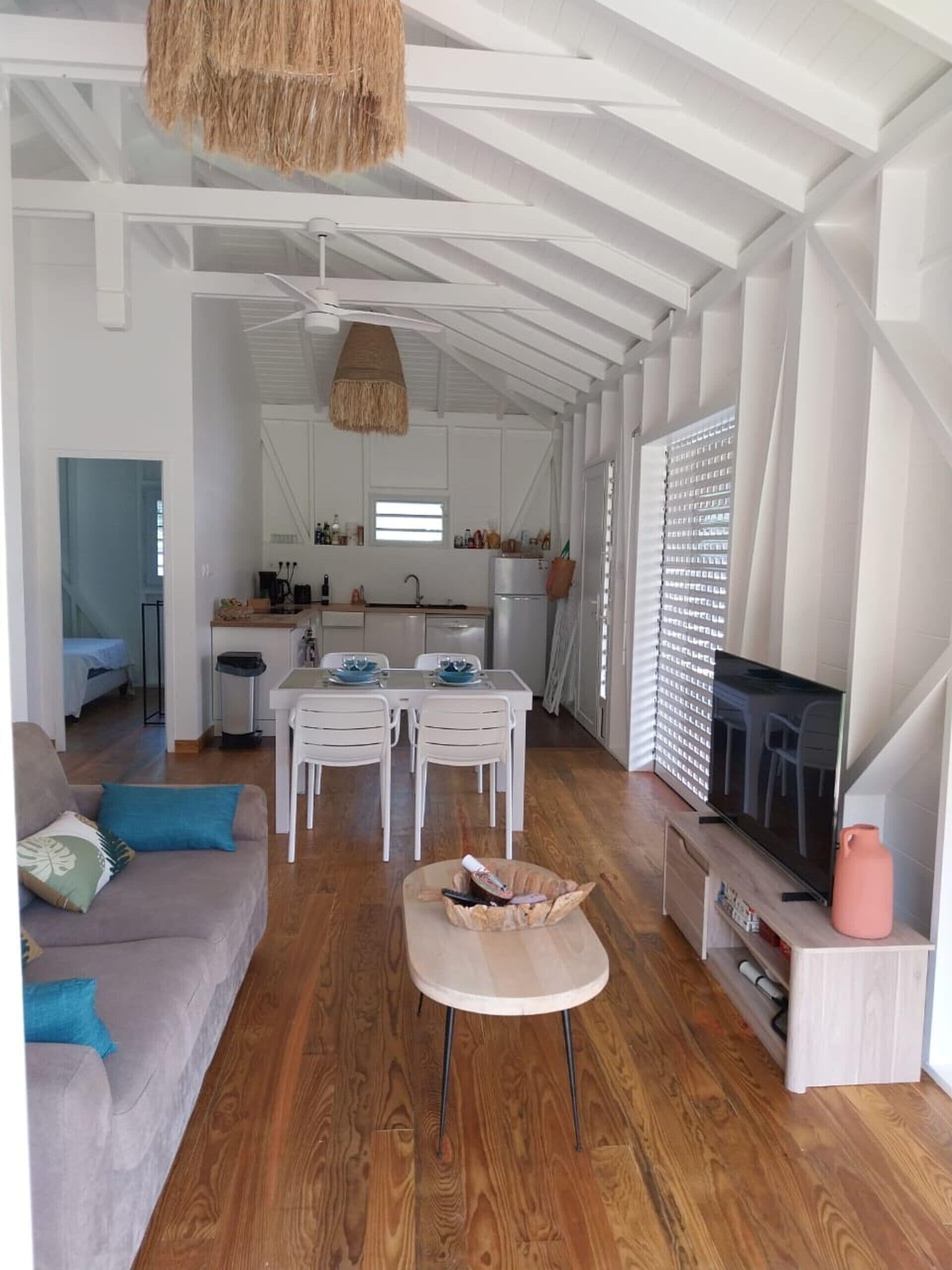 A modern, open-plan living space with a dining area, kitchen, and a TV.