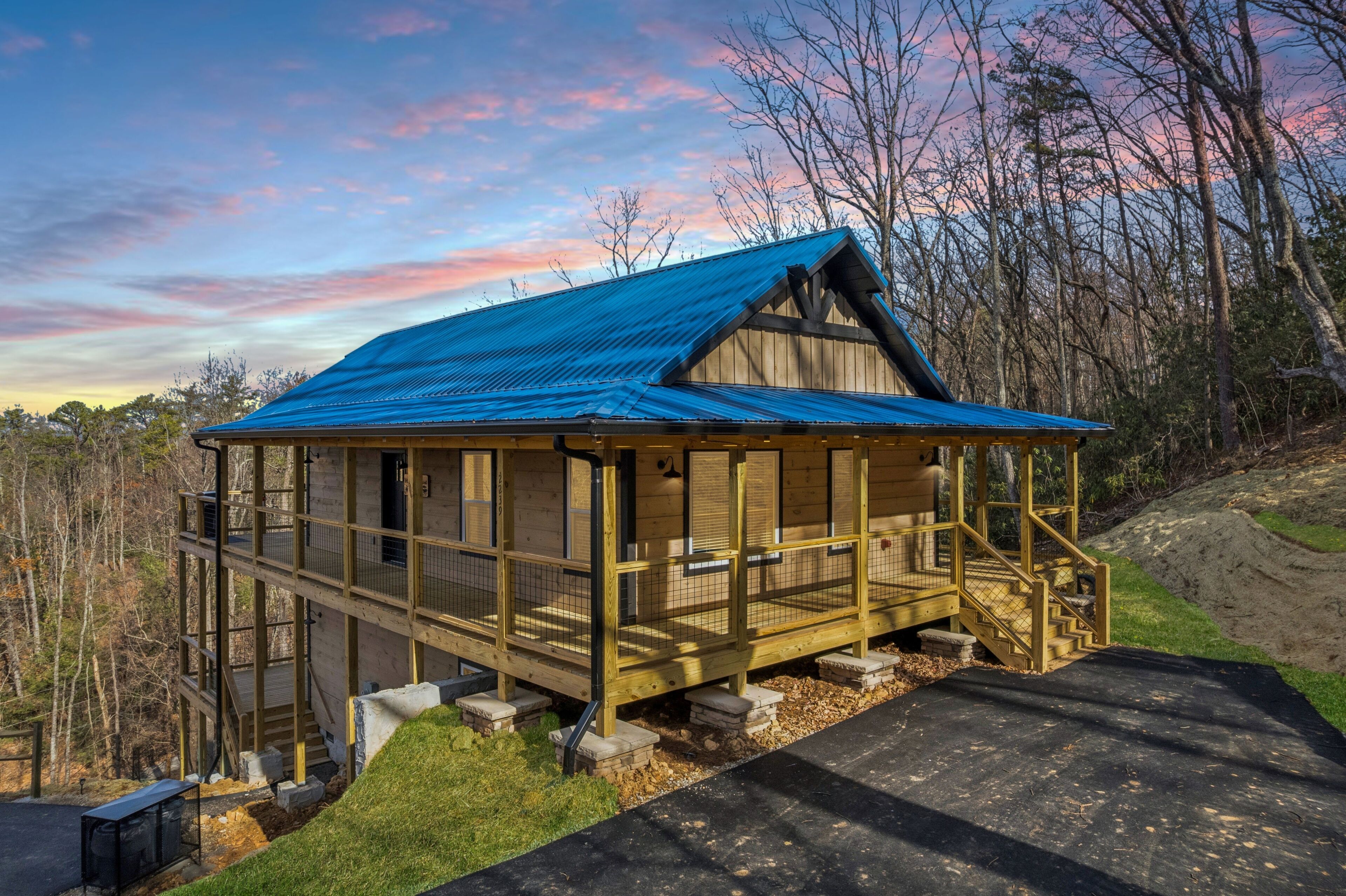 A wooden cabin with a blue roof, a balcony, and a staircase leading to the entrance.
