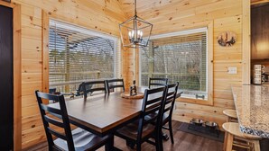 Ein Holzinterieur mit Esstisch, Stühlen und einer Küchenzeile mit Arbeitsplatte und Spüle.