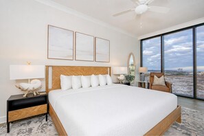 A spacious bedroom with a large bed, a ceiling fan, a view of the city, and a large window. - Phoenix Gulf Shores Ii 1105 4 Bedroom Condo (Gulf Shores)