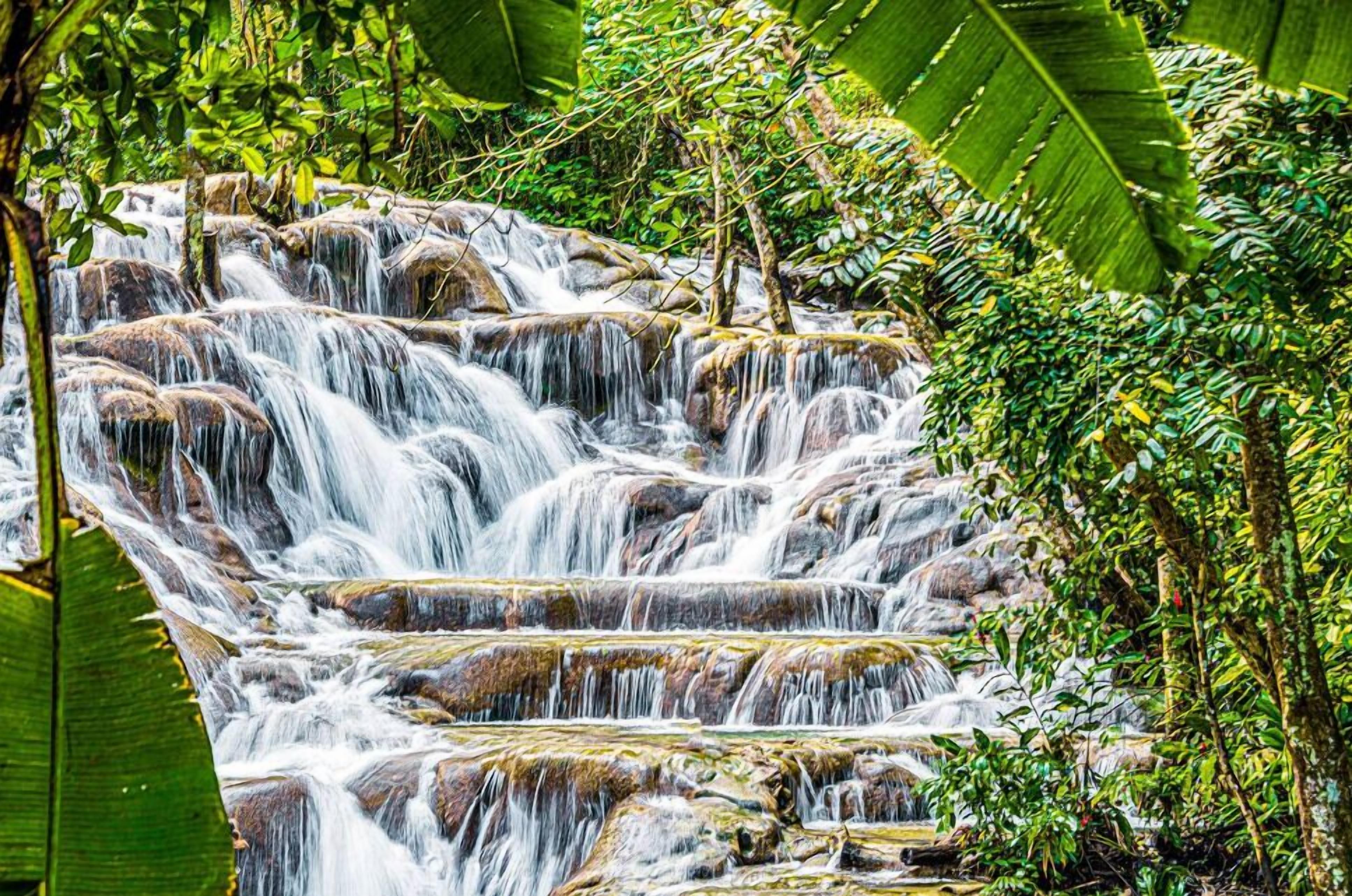 A multi-tiered waterfall surrounded by lush greenery.