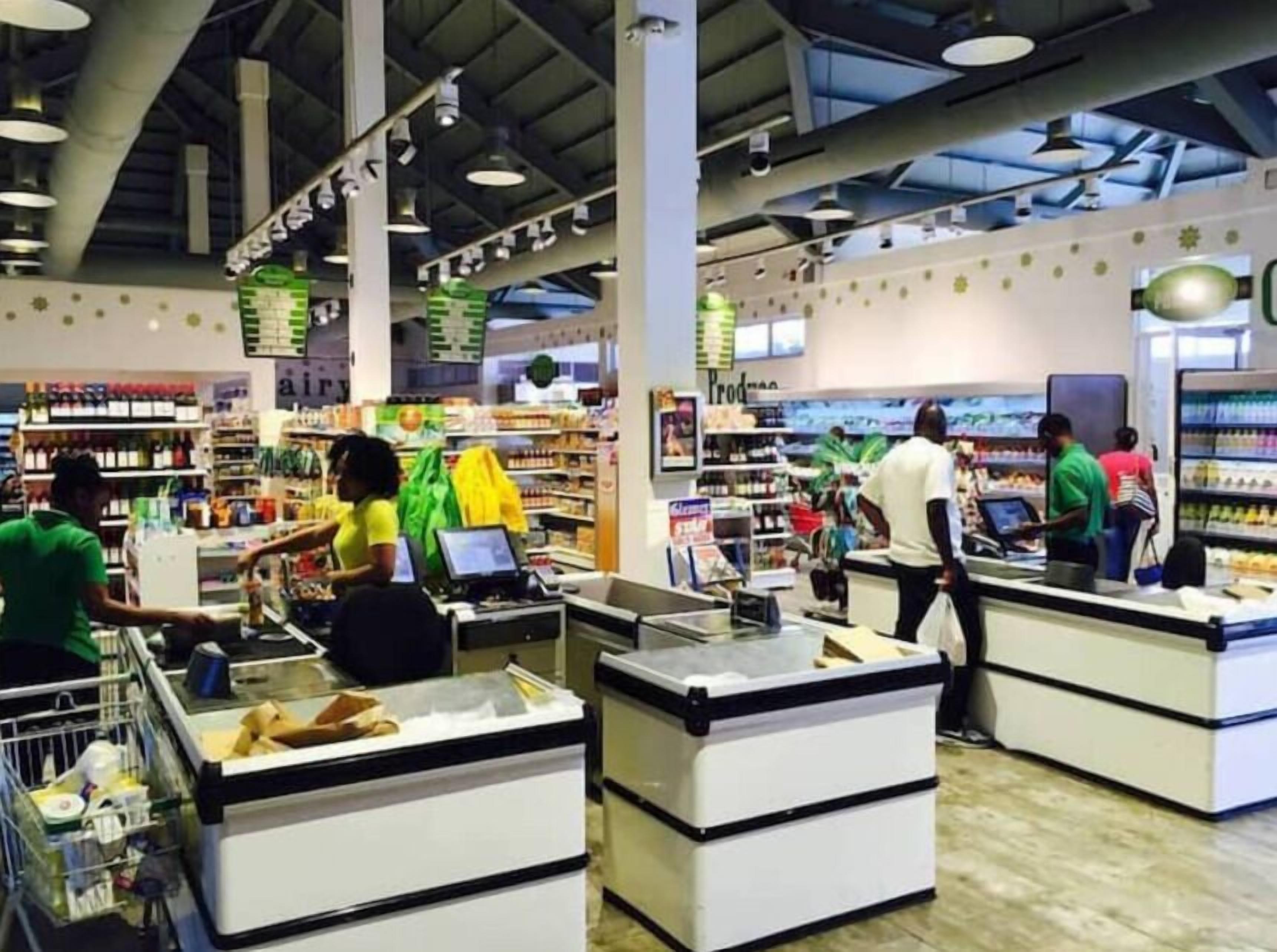 A supermarket with multiple checkout counters, shelves stocked with various products, and customers shopping.