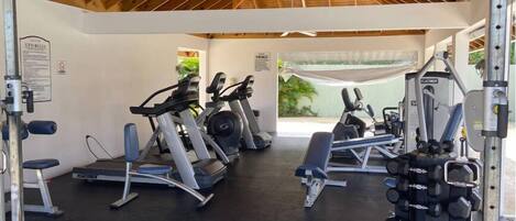A gym with treadmills, weight benches, and dumbbells.
