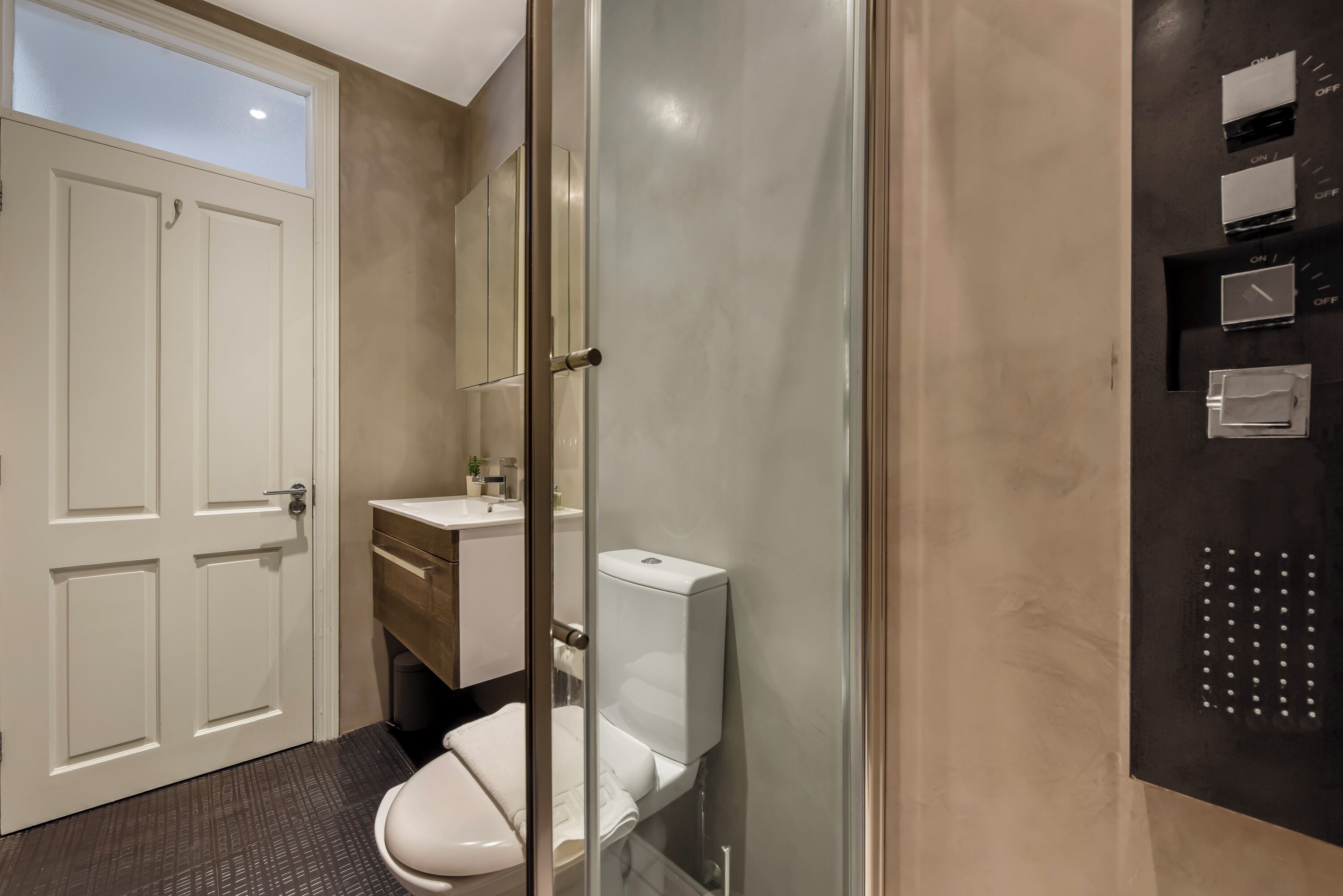 Un baño moderno con inodoro, lavabo y cabina de ducha de vidrio.