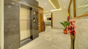 A modern hotel lobby with a marble floor, a reception desk, a wooden reception area, and potted plants. - Hotel AeroStay Bangalore Airport (Bangalore)