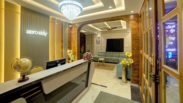 A reception area with a reception desk, a globe, a sofa, and a chandelier. - Hotel AeroStay Bangalore Airport (Bangalore)