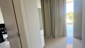Una habitación amplia con un gran ventanal, una puerta corredera y piso de baldosas.