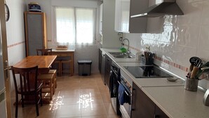 A modern kitchen with a dining area, stainless steel appliances, and a window with sheer curtains. - Villa Villa Maria 10 min. from Puy Du Fou. Ideal for families and groups of friends (CM)