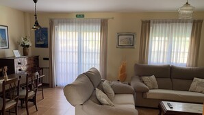 A living room with a sofa, a dining table with chairs, a coffee table, and a chandelier. - Villa Villa Maria 10 min. from Puy Du Fou. Ideal for families and groups of friends (CM)