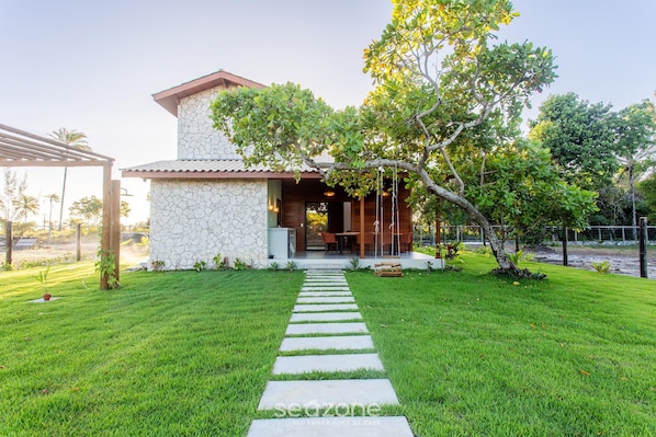 Una casa de fachada de piedra, un sendero pavimentado que lleva a la entrada y un césped bien cuidado.