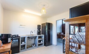 Una cocina compacta con pileta integrada, un refrigerador negro y una cafetera.
