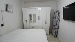 Ein Schlafzimmer mit einem Bett, einem Kleiderschrank, einem Fernseher und einer Heizung.