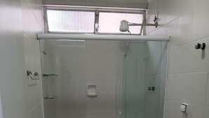 Ein Badezimmer mit einer gläsernen Duschkabine, einer Toilette und einem Waschbecken mit Marmorplatte.