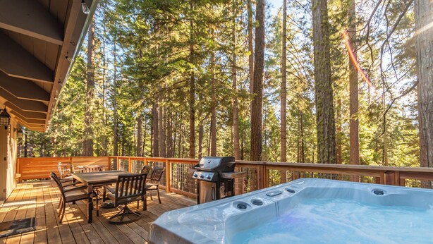 Eine Holterrasse mit Whirlpool, Sitzgelegenheiten und Grill.