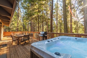Eine Holterrasse mit Whirlpool, Sitzgelegenheiten und Grill.