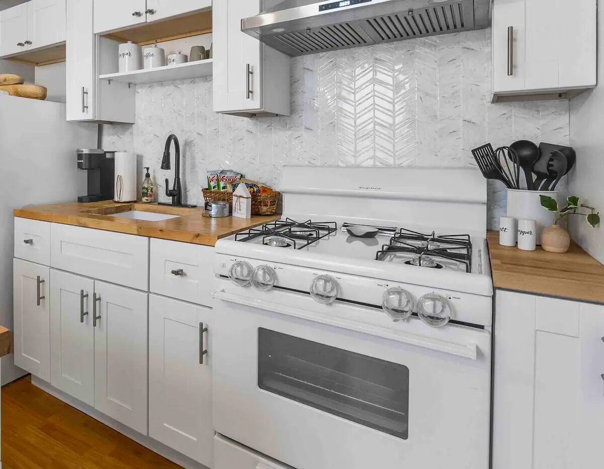 Una cocina moderna con gabinetes blancos, una estufa a gas y un horno empotrado.
