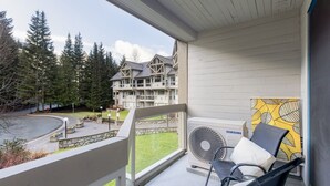 Un balcon avec un climatiseur Samsung, un mur jaune à motifs et une vue sur un immeuble doté de nombreuses fenêtres et d’un chemin pavé.