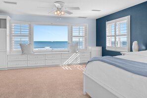 A bedroom with a large window overlooking the ocean, a bed with a blue blanket, and a ceiling fan. - Seaside Splendor, The pinnacle of luxury. Brand New Oceanfront Rental (Saint Augustine)
