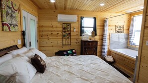 Une chambre dans une cabane en bois, avec un lit, une commode et une fenêtre donnant sur un paysage agréable.