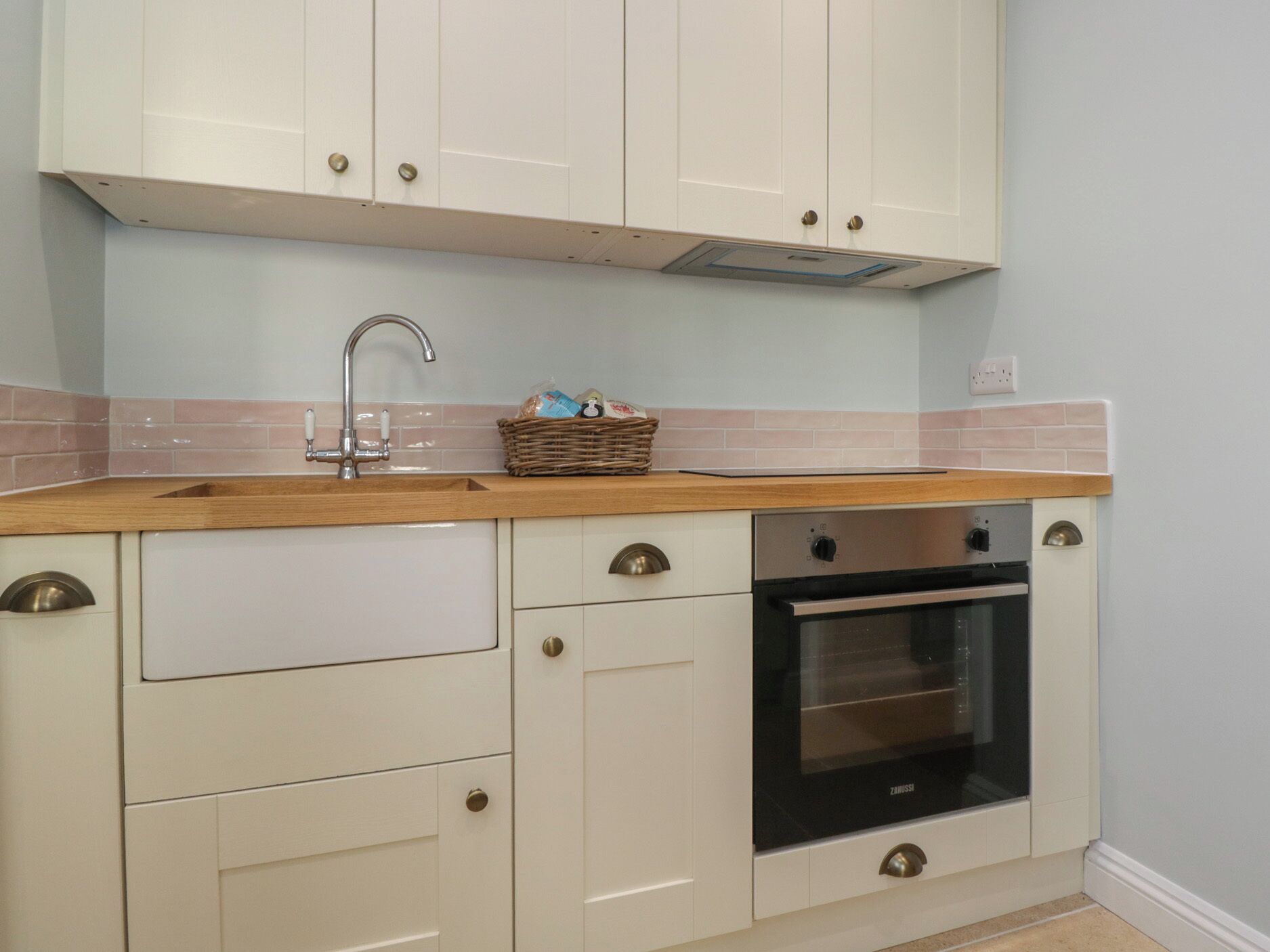 A kitchen with white cabinets, a wooden countertop, a stainless steel oven, and a sink.