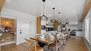 Una cucina moderna con pavimento in legno, un tavolo da pranzo in vetro e illuminazione a sospensione.